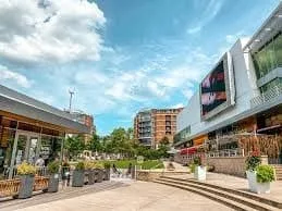 Modern shopping plaza in Falls Church, VA, featuring outdoor seating, greenery, and vibrant storefronts, reflecting the community's inviting atmosphere.